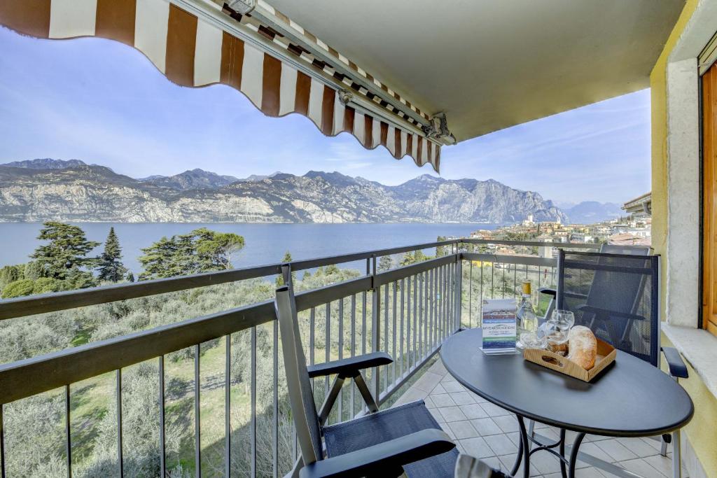 balcón con mesa y vistas al agua en Residence La Perla Malcesine, en Malcesine