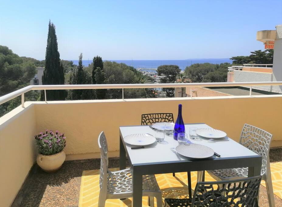 une table blanche et des chaises sur un balcon dans l'établissement Les Orangers de Santa Lucia, vue mer et port, St Raphaël, à Saint-Raphaël