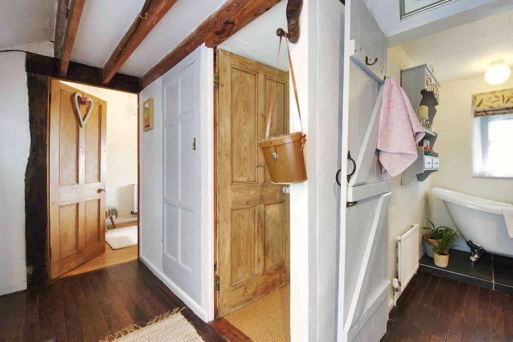 a bathroom with a wooden door and a tub at Quincecote mini guest wing in Hartland