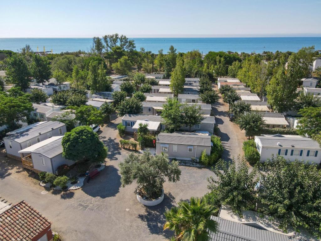 - une vue aérienne sur un parking avec des arbres et des maisons dans l'établissement Camping Pleine Mer, à Vias