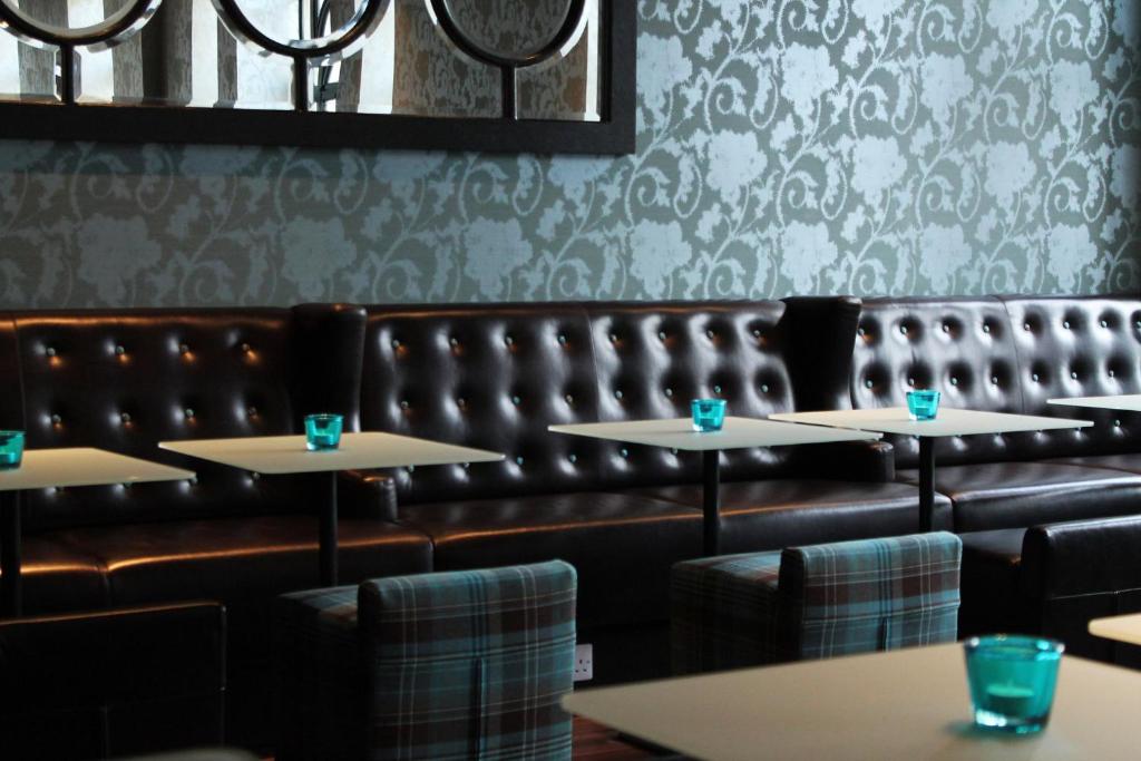 uma sala de jantar com mesas e um banco de couro em Motel One Edinburgh-Princes em Edimburgo