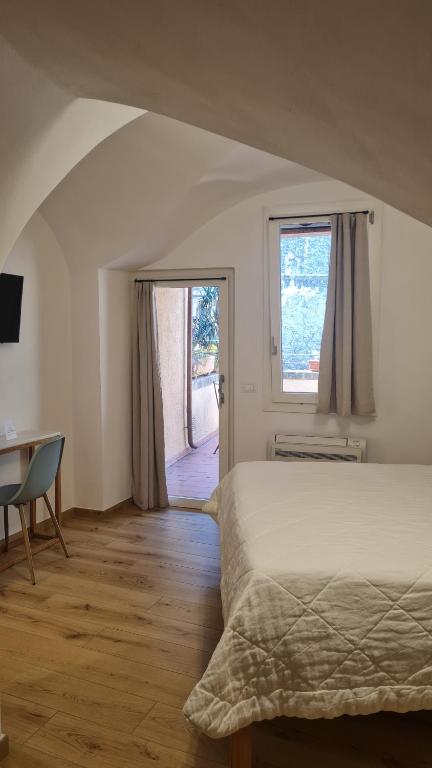 um quarto com uma cama, uma secretária e uma janela em Federico II - Rooms and Breakfast em Borgio Verezzi