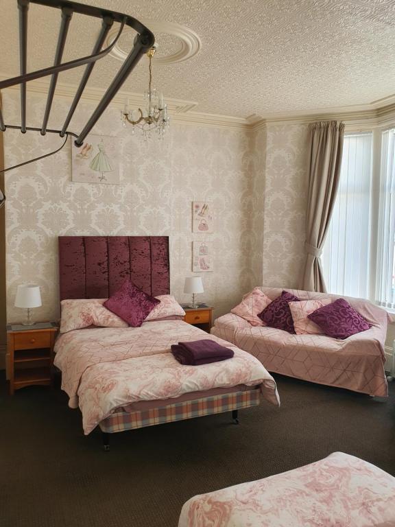 una camera con due letti e un lampadario a braccio di Windsor House Hotel a Blackpool