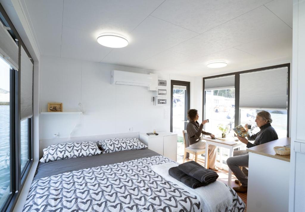 1 dormitorio con 1 cama y 2 personas sentadas en una mesa en ALMALO Floating House - Casa Galleggiante en Procida