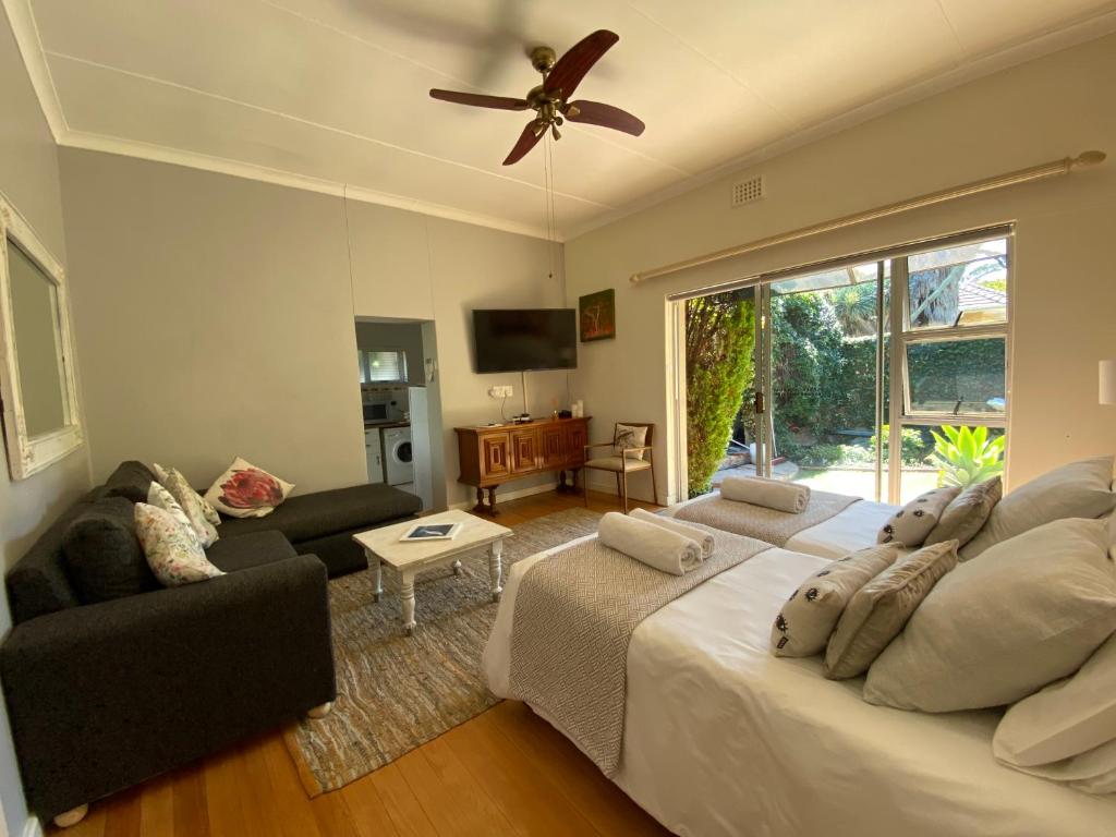 a living room with a bed and a ceiling fan at Vredelust Cottage in Bellville