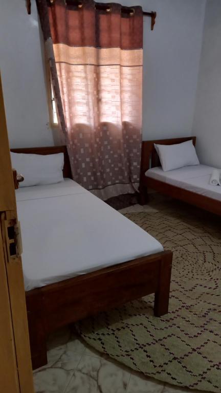 two twin beds in a room with a window at JAHA in Lamu