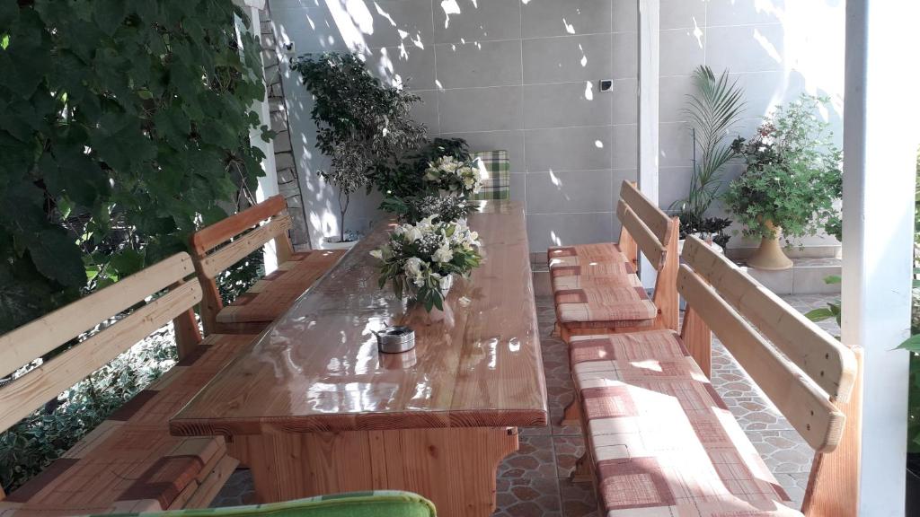 ポモリエにあるVeda Guest Houseの花の上に並ぶ長い木製テーブル