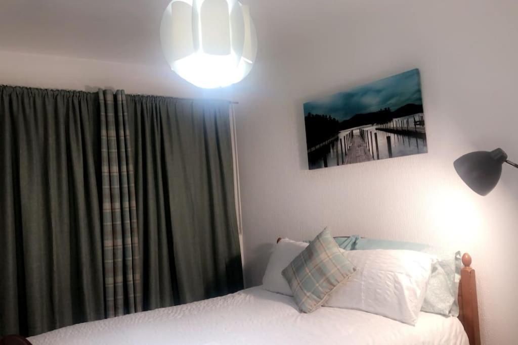 1 dormitorio con cama, lámpara y ventana en Entire One Bedroom Apartment Near Stratford, en Londres