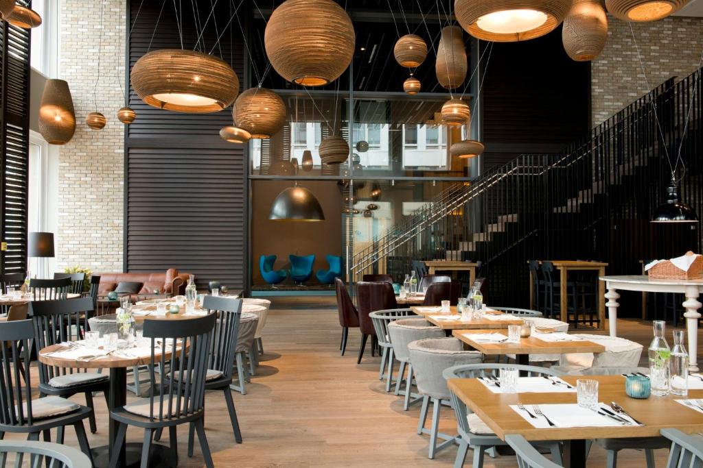 a restaurant with tables and chairs and lights at Motel One München-Campus in Munich