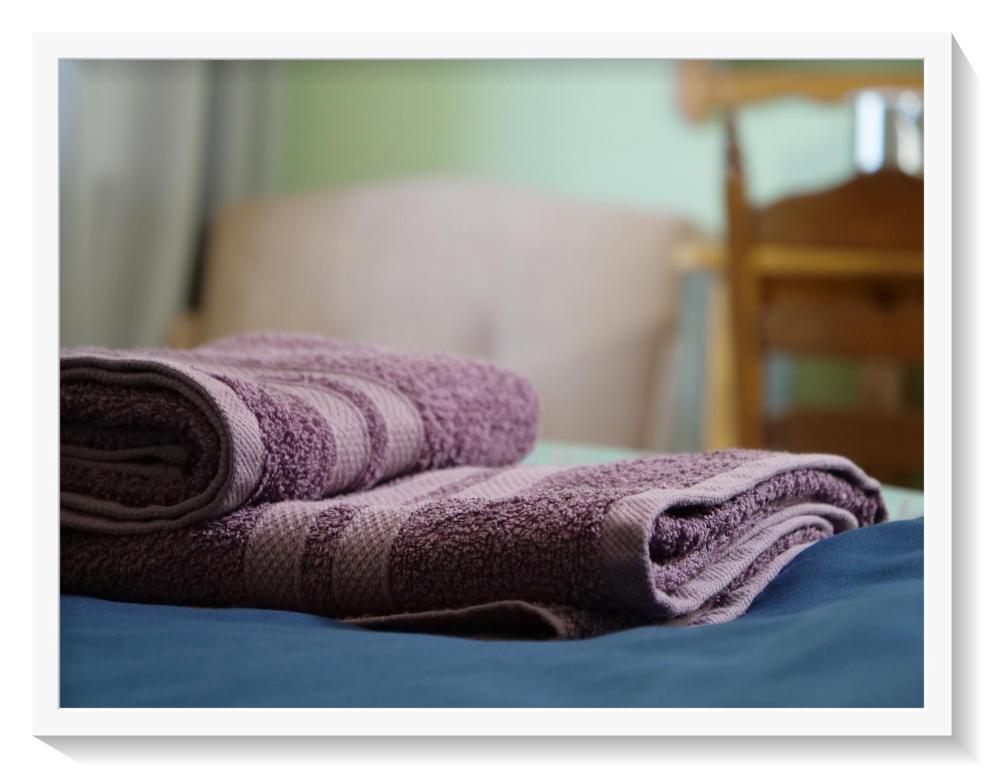 uma pilha de toalhas roxas sentadas em cima de uma cama em Agroturystyka Chłopy em Sarbinowo