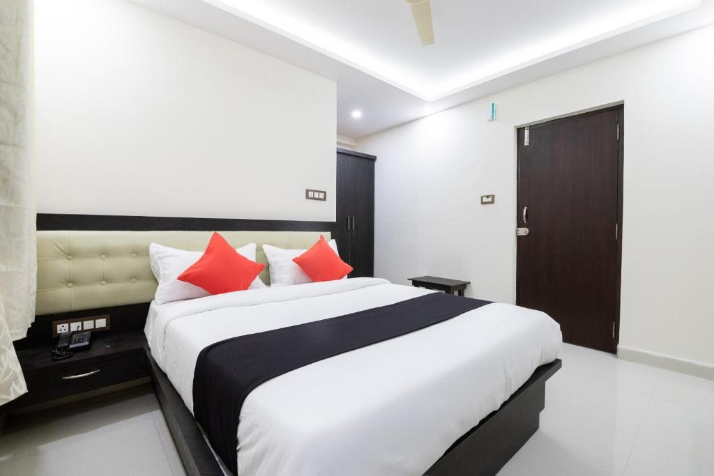 um quarto com uma grande cama branca com almofadas vermelhas em Super Capital O Choice Regal Suites Near Ragigudda Sri Prasanna Anjanayeswamy Temple em Bangalore