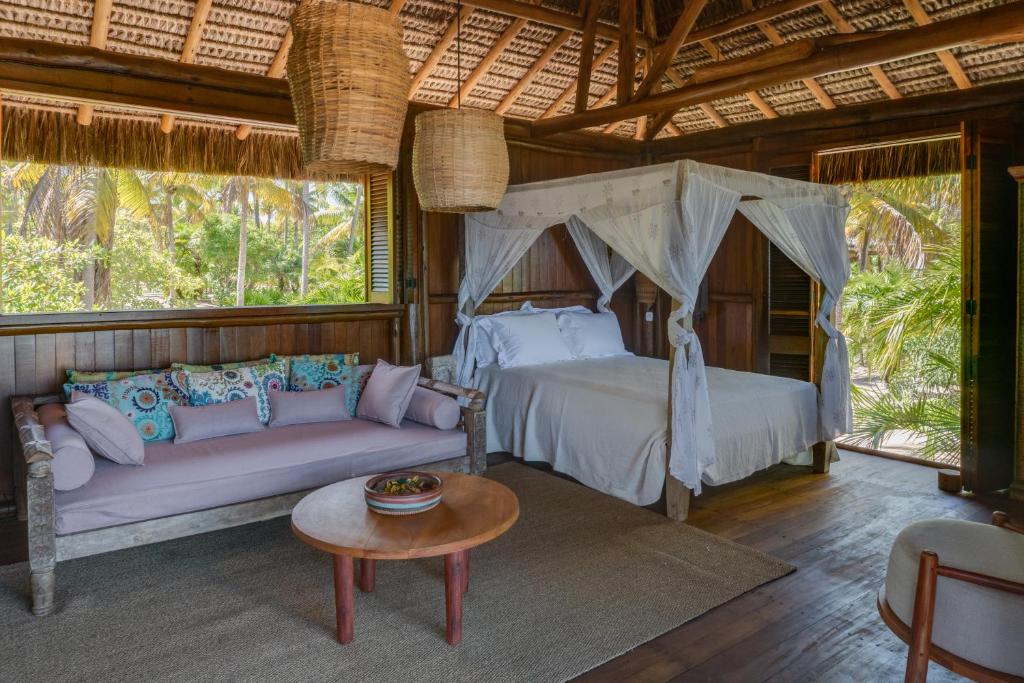 a bedroom with a bed and a couch and a table at Oka Maraú I Charming Bungalows in Marau