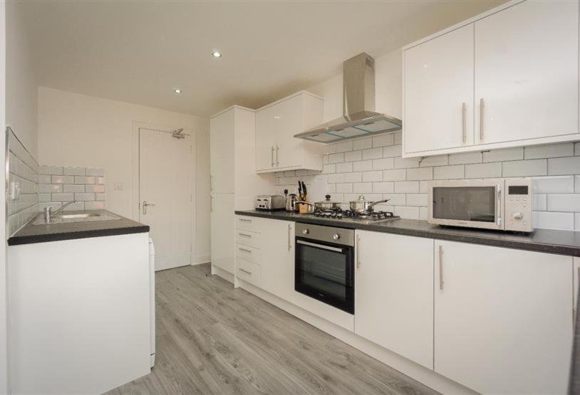 uma cozinha com armários brancos e um forno com placa de fogão em King St Contractor Accommodation 6 bed 6 bath free parking for vans em Wallasey