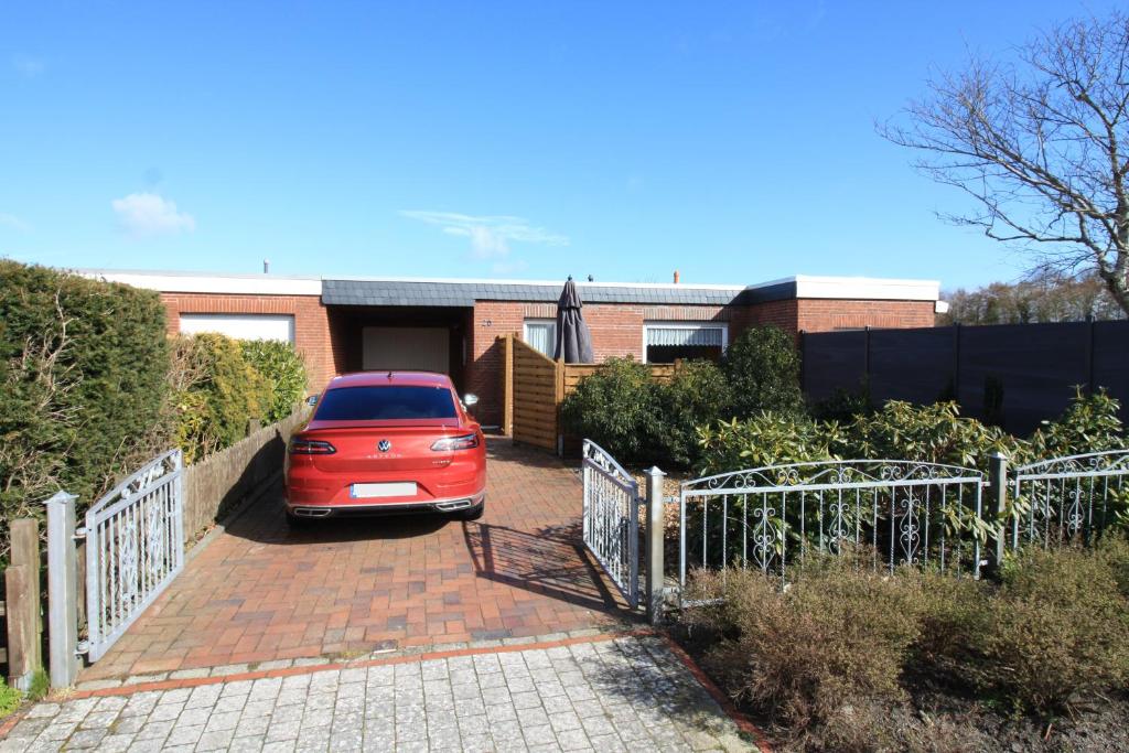 um carro vermelho estacionado em frente a uma casa em Haus Ingrid em Norddeich