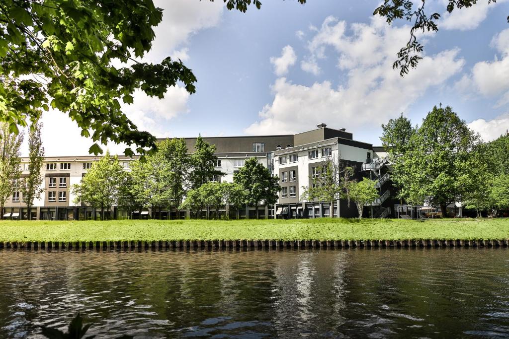 ein Gebäude neben einem Wasserkörper in der Unterkunft GINN Hotel Berlin Potsdam in Teltow