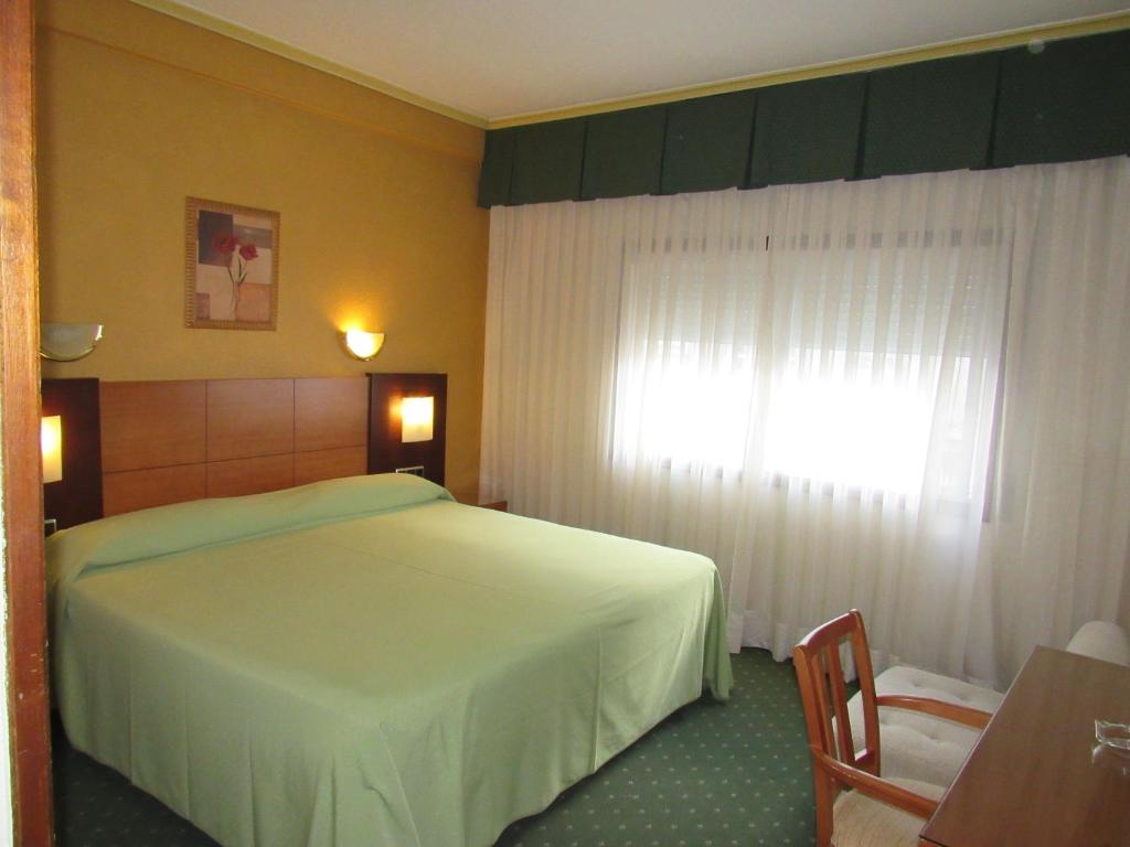 a hotel room with a bed and two lamps at Hotel Virgen del Camino Pontevedra in Pontevedra