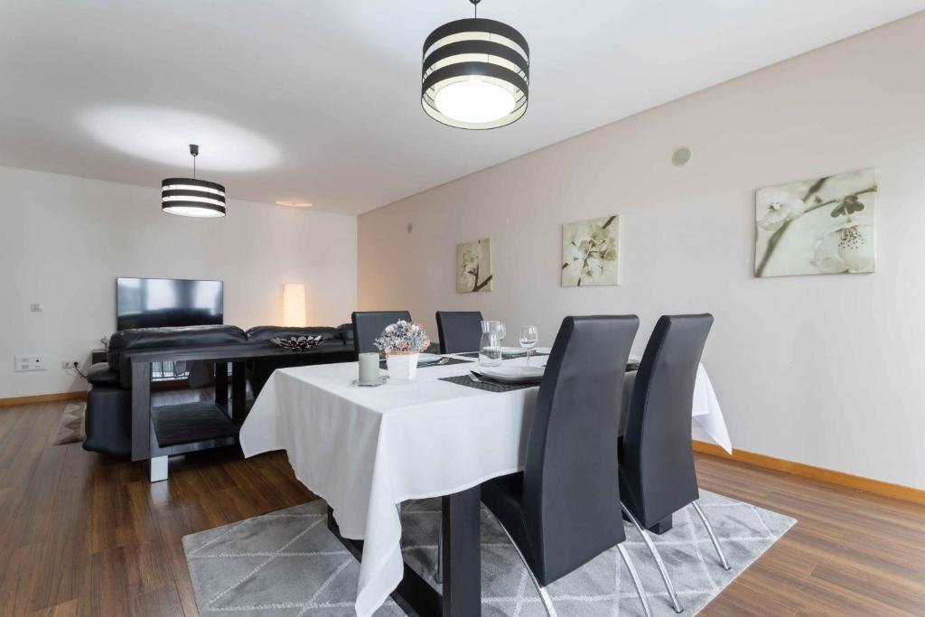 uma sala de jantar com uma mesa branca e cadeiras pretas em Modern & Elegant 2 bedroom in Amadora by GT House em Amadora