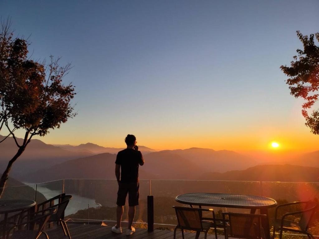 a man standing on a balcony looking at the sunset at Ming Ging Farm in Ren&#39;ai
