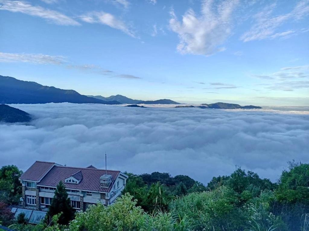 a house on a hill above a sea of clouds at Ming Ging Farm in Ren&#39;ai