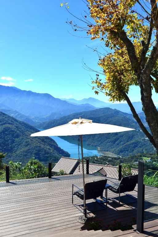 a table and two chairs under an umbrella on a deck at Ming Ging Farm in Ren&#39;ai