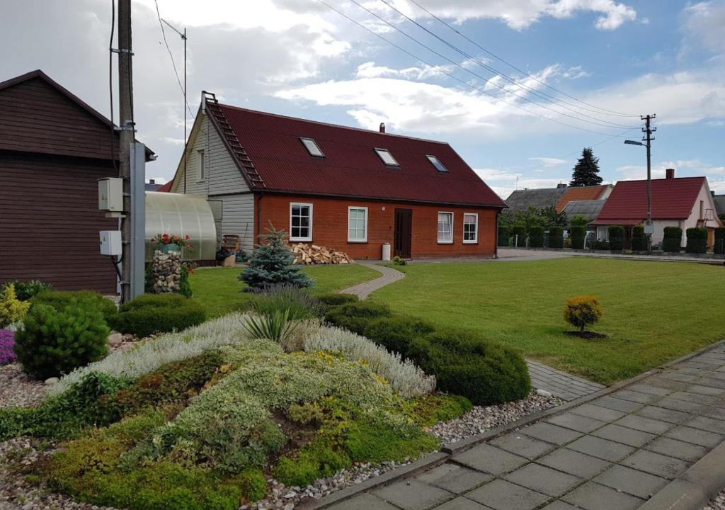 ein Haus mit einem roten Dach und einem grünen Hof in der Unterkunft Vila House in the city center of Ukmerge in Ukmergė