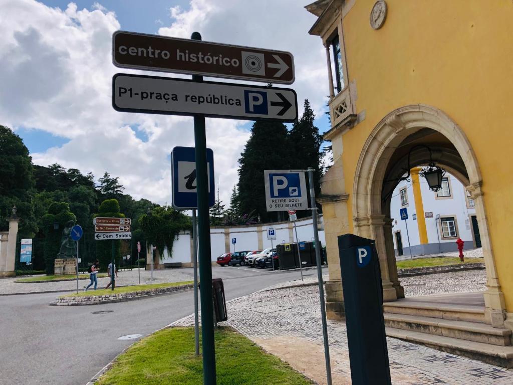 eine Stange mit Straßenschildern vor einem Gebäude in der Unterkunft Pé do Castelo Casinha in Tomar