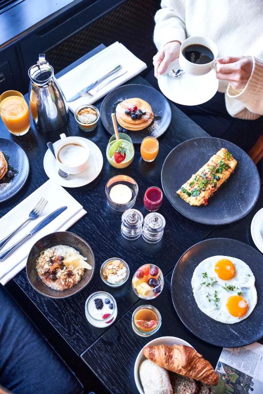 a table with plates of breakfast food on it at Hotel Continental in Oslo