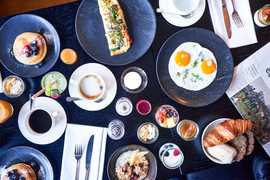 a table topped with plates of breakfast foods and coffee at Hotel Continental in Oslo