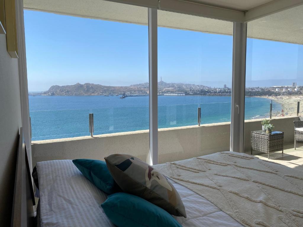 a bedroom with a bed and a view of the ocean at Departamento Playa Herradura Primera Línea in Coquimbo