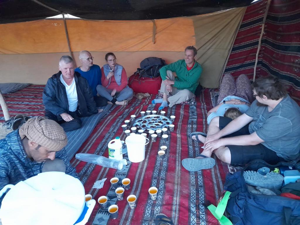 Feynan wild camp في Al Khuraybah: مجموعة من الناس يجلسون في خيمة