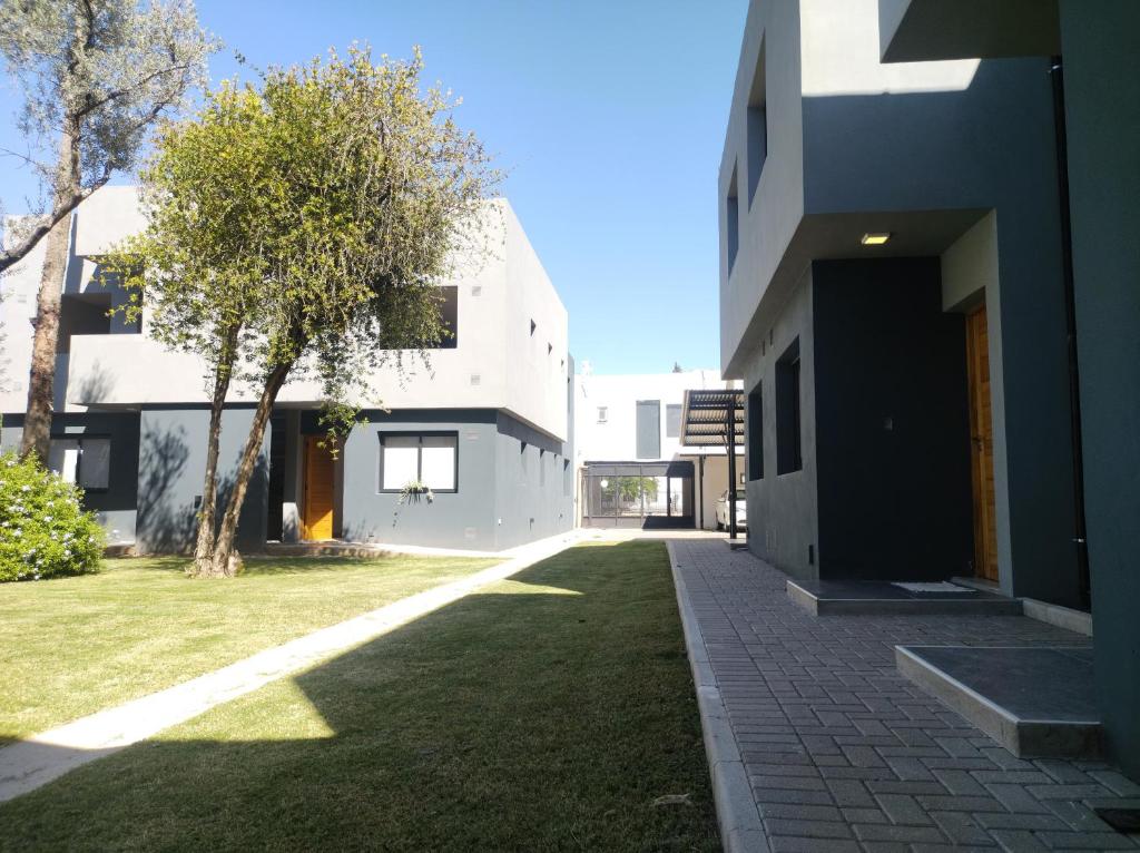 un edificio con un patio de césped junto a un árbol en Complejo Claret Departamento B, Zona Norte en Córdoba