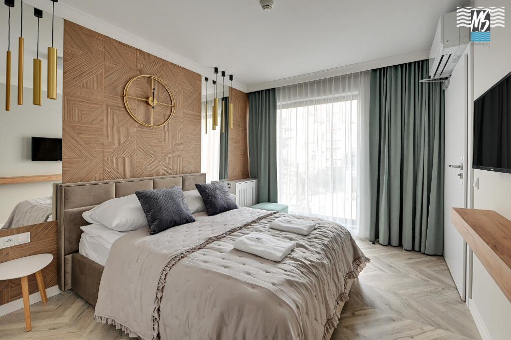 a bedroom with a large bed with a clock on the wall at MS Apartments Rest 1.0 in Sopot