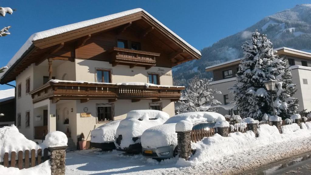 a house with snow covered cars in front of it at Haus Mariandl in Westendorf