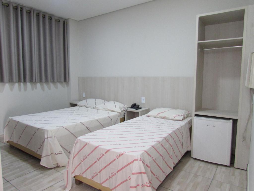 2 camas en una habitación con sábanas blancas y rosas en Hotel Salomão - Próximo a 25 de Março, Bom Retiro, Brás e Rua Santa Efigênia, a 2 minutos do Mirante Sampa Sky e pista de Skate Anhangabaú en São Paulo
