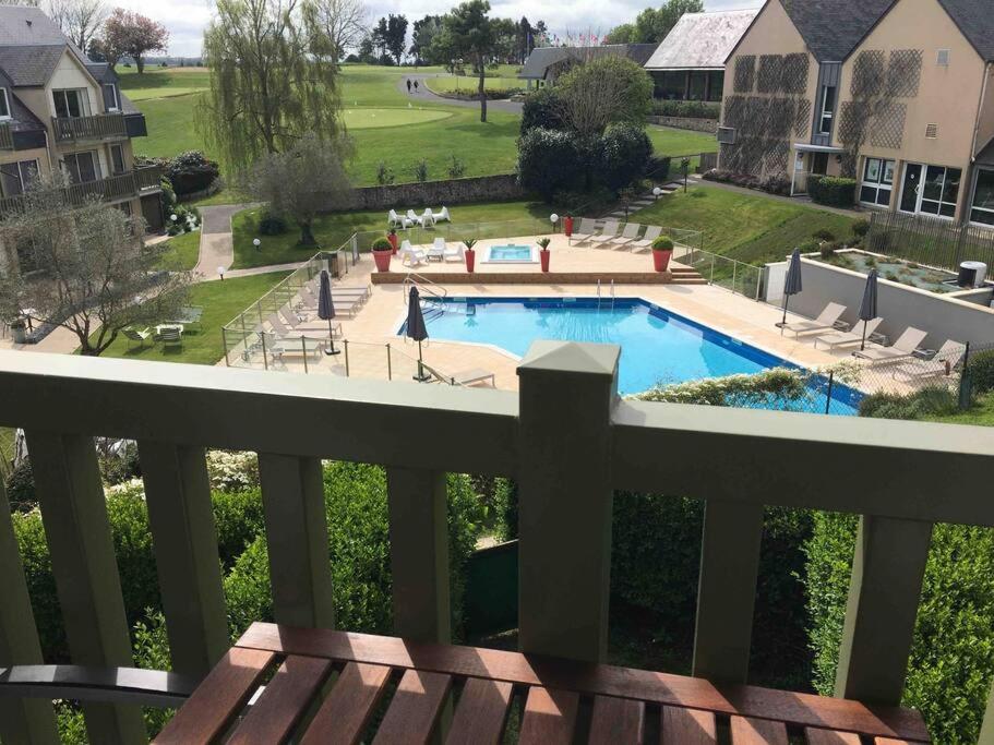 a view of a swimming pool from a balcony at Studio Golf piscine D Day in Port-en-Bessin-Huppain