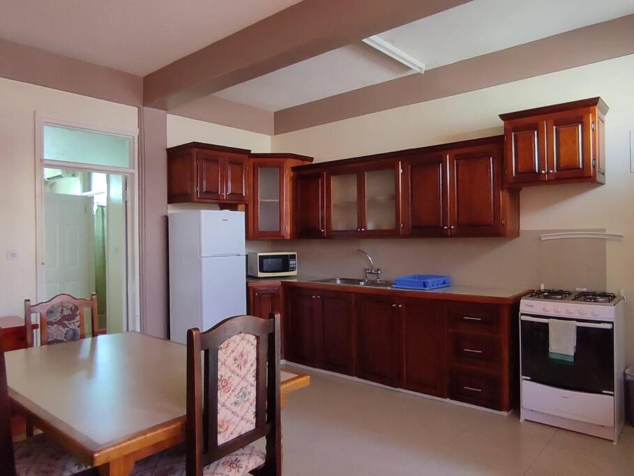 eine Küche mit Holzschränken, einem Tisch und einem Kühlschrank in der Unterkunft Iso’s Vacation Rental Apartment #8 in Portsmouth