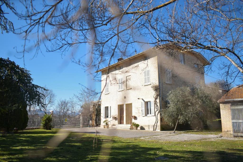 a large white house with a tree at Il Glicine in Falerone