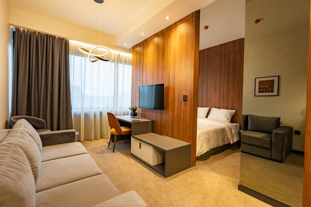 Habitación de hotel con cama, escritorio y TV. en Hotel Element en Novi Sad