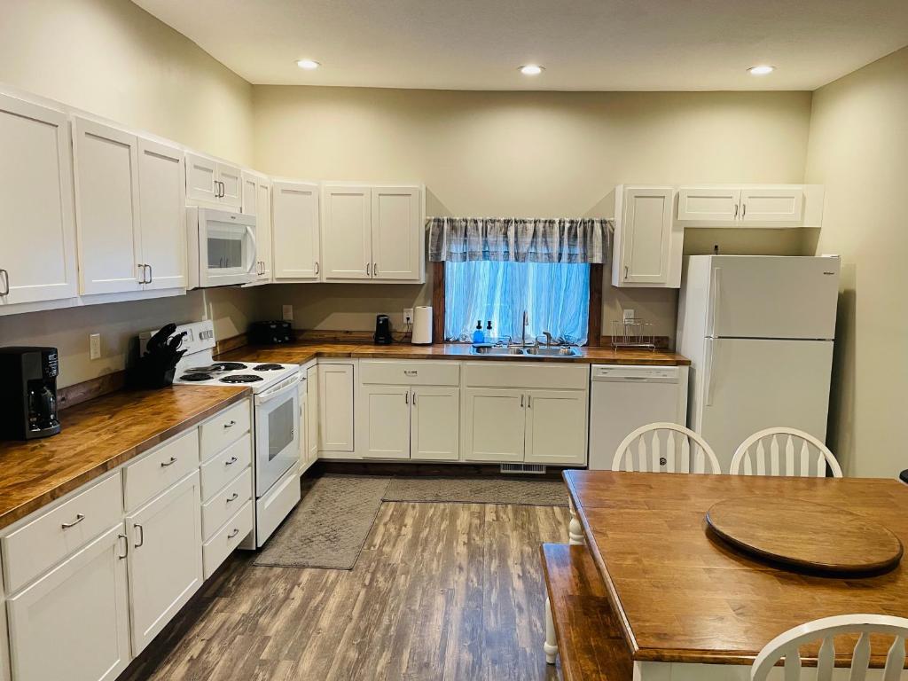 a kitchen with white cabinets and a wooden table at Modern Farmhouse 3 Bed, 2 Bath Apartment, Sleeps 7, Lots of Space, Steps to Downtown, Honeywell & Eagles Theater in Wabash