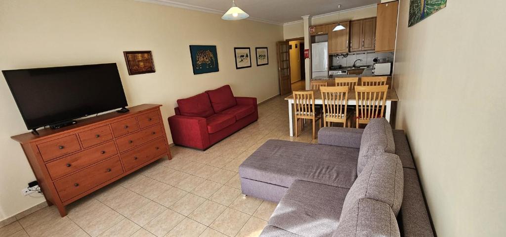ein Wohnzimmer mit einem Sofa und einem TV sowie eine Küche in der Unterkunft Open Space - Albufeira in Albufeira