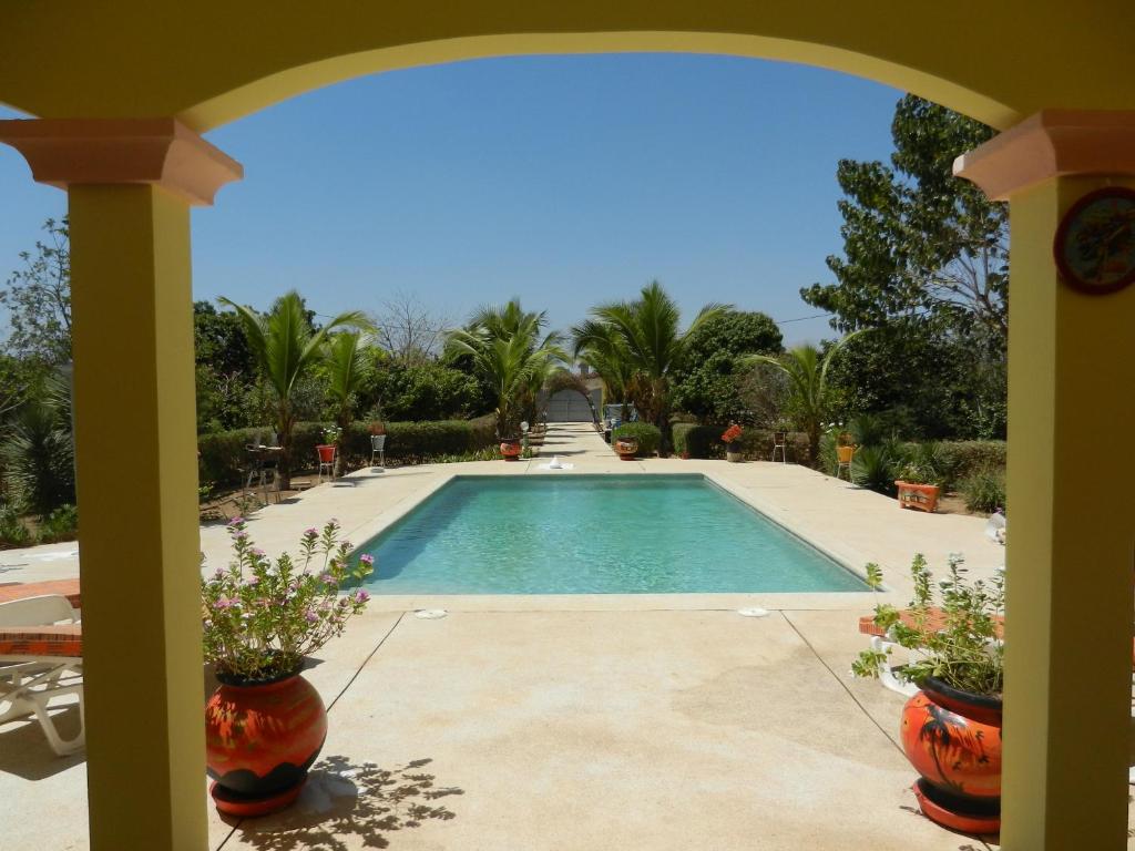 einen Pool in einem Garten mit Palmen in der Unterkunft Villa au Tamtam in Gandigal