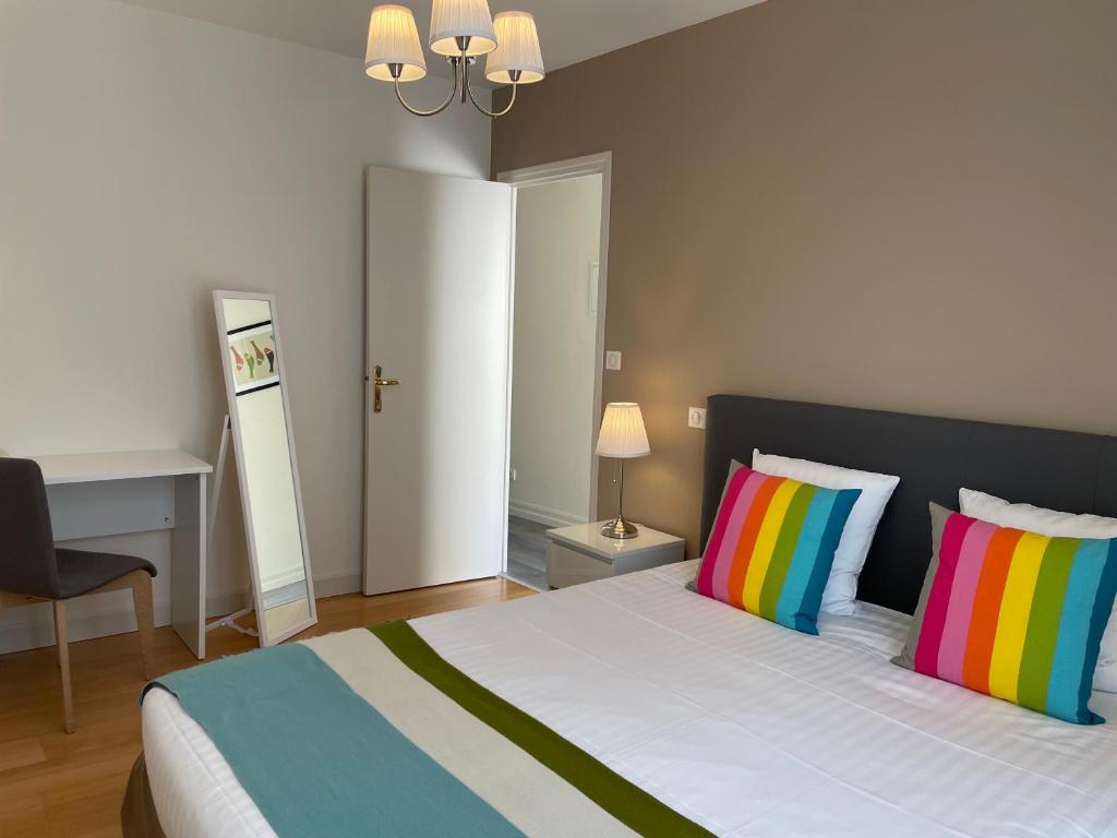 una camera da letto con un letto con cuscini colorati e una scrivania di Appartement Coeur de Ville a Chinon