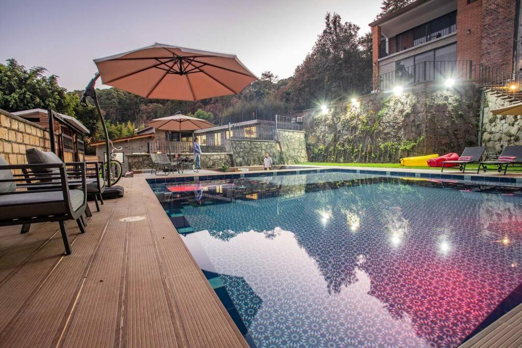 a swimming pool with an umbrella next to a building at Incredible Apartment Avándaro in Valle de Bravo