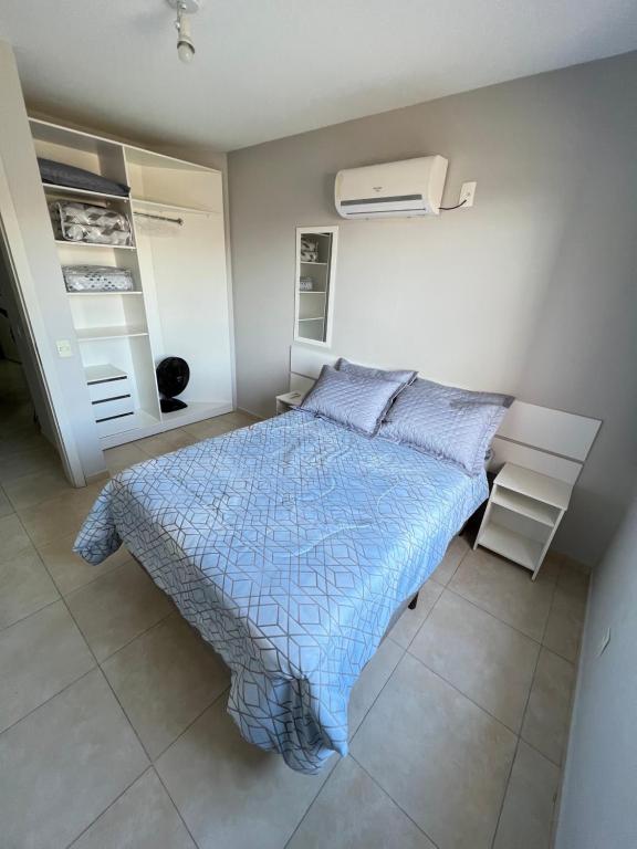 a bedroom with a bed with a blue comforter at Apartamento beira mar em Ponta das Canas in Florianópolis