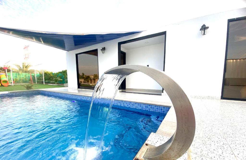 a pool with a water slide in front of a house at Luxury Farm with Swimming Pool and BBQ in Al Rahba