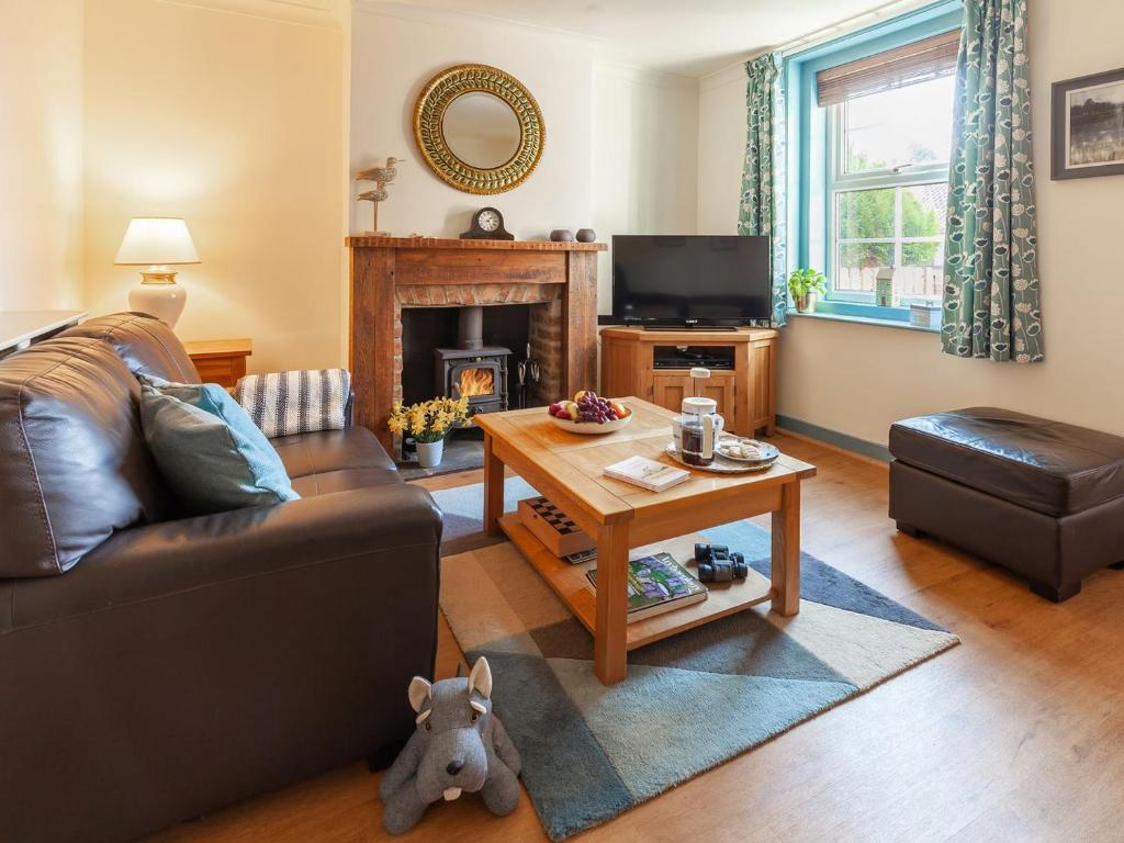 a living room with a couch and a table at Elf Cottage in Heacham