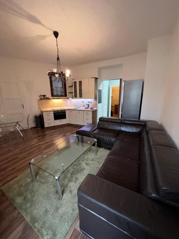 een woonkamer met een leren bank en een glazen salontafel bij Folimanka apartment in Praag