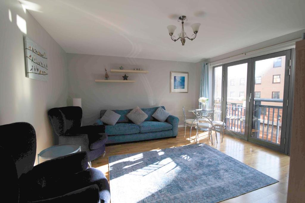 ein Wohnzimmer mit einem blauen Sofa und einem Tisch in der Unterkunft Bright Contemporary Merchant City Flat in Central Location in Glasgow