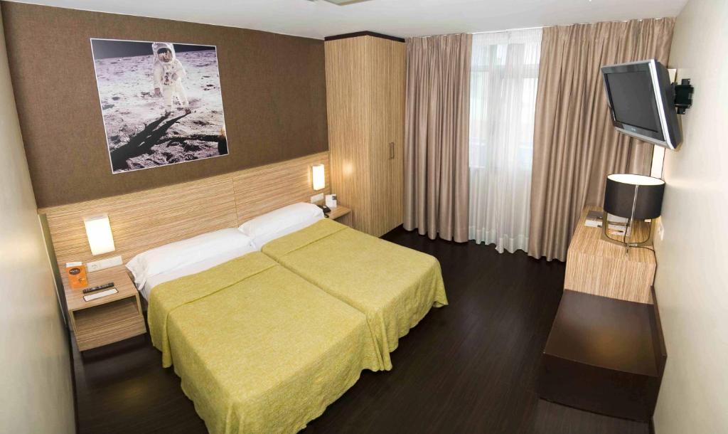 a hotel room with a bed and a flat screen tv at Hotel Moon in A Coruña