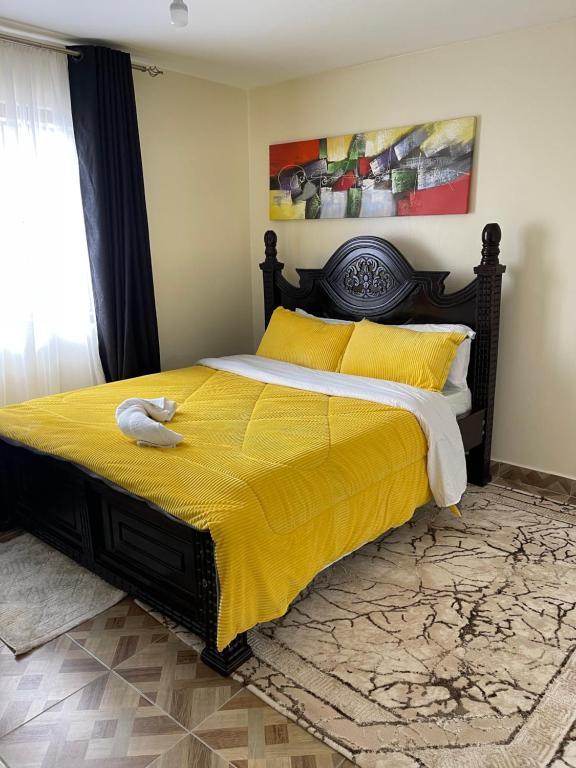 1 dormitorio con 1 cama grande con manta amarilla en Inviting 3-Bed Apartment in Nairobi en Nairobi
